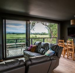 A living room with a sofa and dining area overlooking a view at The Red House in Farndon