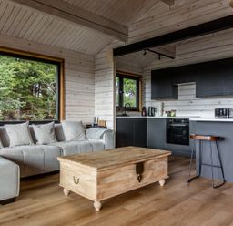 A living room with a sofa and kitchen area at The Larch House in Farndon