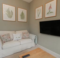 A living room with a white sofa and TV at Granary Cottage in 