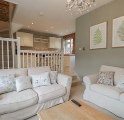 A living room with sofas and a kitchen area at Granary Cottage in 