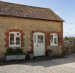 An exterior view of a cottage with plants outside at Granary Cottage in Lacock