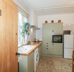 A kitchen with sink, washing machine, and cabinets at Apartment 1 The Bridge at Stanford Hotel near Great Witley