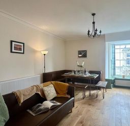 A dining room with a table and sofa at Llanrwst Apartment