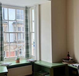 A sitting area with a window and green table at Llanrwst Apartment