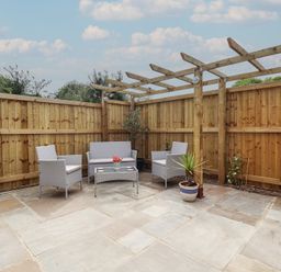 A garden with seating area and flower pot at Pear Tree Lodge in Alford