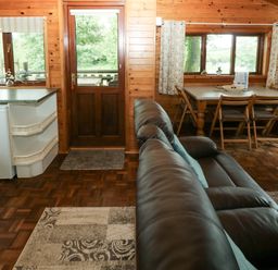A living room with a sofa and a dining table at Oak Lodge in Mynydd Cerrig near Porthyrhyd