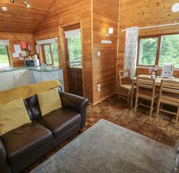 A living room with a sofa and dining area at Ash Lodge Mynydd Cerrig near Porthyrhyd