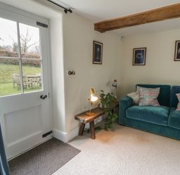 A living room with a sofa and a door leading to the outside at West Cottage in Myddfai near Llandovery