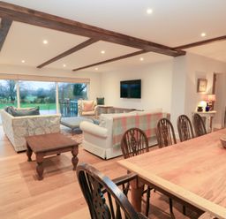 A living room with a sofa and dining area at Peewit Coach House in Moreton-in-Marsh