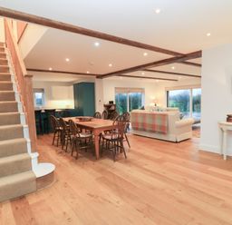 A living room with a staircase, dining table, and sofa at Peewit Coach House in Moreton-in-Marsh