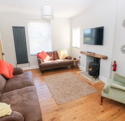 A living room with a sofa and television at Hawthorns Swansea