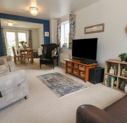 A living room with a sofa and dining area at June Cottage in Wool