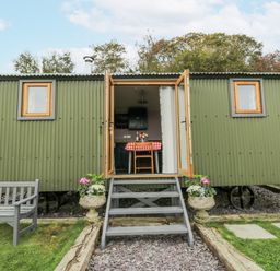 A shepherd's hut with steps and a bench at Brondel Luxury Shepherd's Hut