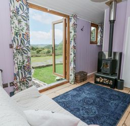 A living room with a wood stove and windows at Brondel Luxury Shepherd's Hut