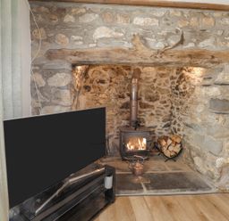 A living room with a wood stove and television at Clawddcam in Mathry