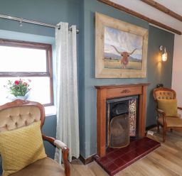 A living room with chairs and a fireplace at Clawddcam in Mathry
