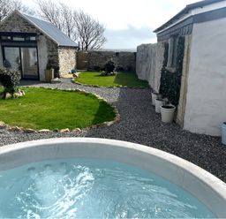 A garden with a hot tub and stone walls at Clawddcam Mathry
