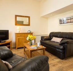 A living room with a sofa and television at 2 Riverside Cottages in Ambleside