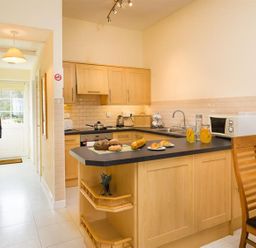 A kitchen with a countertop and dining table at 2 Riverside Cottages Ambleside