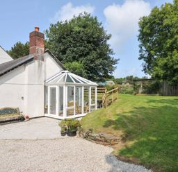 A garden with a conservatory and bench at Upper Court Cottage in Broad Langdon near Wainhouse Corner