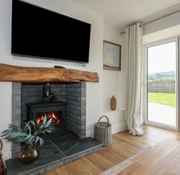 A living room with a fireplace and television at Criw in Bryncroes near Sarn Meyllteyrn