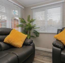 Two armchairs with cushions and a plant in a living room at Owls Nook Lodge Langdale 9 White Cross Bay near Windermere