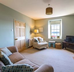 A living room with a sofa and a television at Zenobia in New Quay