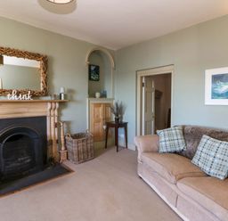 A living room with a sofa and fireplace at Zenobia in New Quay