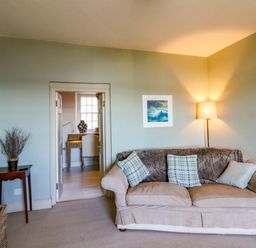 A living room with a sofa and lamp at Zenobia New Quay