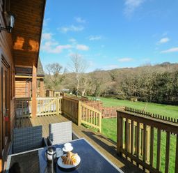 An outdoor area with a table and chairs overlooking a field at Trevano in St Breward