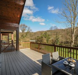 A deck with a table and chairs overlooking trees at Heligan in St Breward