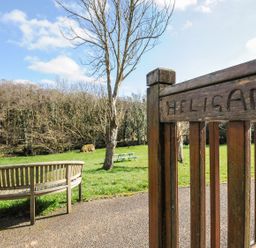 A picnic area with a wooden bench and gate at Heligan in St Breward