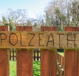 A wooden sign reading Polzeath near a fence at Polzeath in St Breward