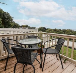 A balcony with a table and chairs at I C Lundy Too near Bideford Bay Holiday Park