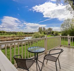 A deck with chairs and a table overlooking a pond at The Dragonfly in Bewholme near Hornsea