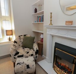 A living room with an armchair and fireplace at Cariad Cottage in Hereford