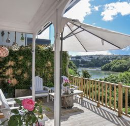 A deck with chairs and a table overlooking a river at Mayhurst in Looe