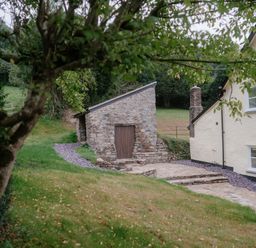 A stone building and patio area at Holwell Farmhouse in Bampton