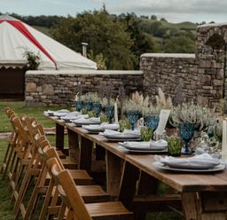 An outdoor dining area with a long table set up at Holwell Farmhouse in Bampton