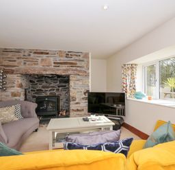 A living room with a sofa and fireplace at Rosewin Farmhouse near St Minver