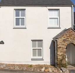 A facade of a house with windows and a stone archway at Wood Cottage