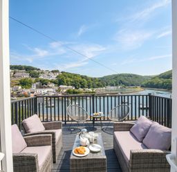 A balcony with chairs and a table overlooking water at Overdale