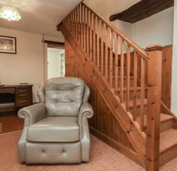 A living room with a chair and staircase at Denhill Cottage