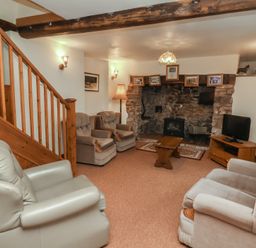 A living room with a fireplace and seating at Denhill Cottage