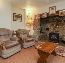 A living room with two armchairs and a table at Denhill Cottage