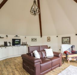 A living room with a sofa and kitchen area at Yr Awen in Lampeter