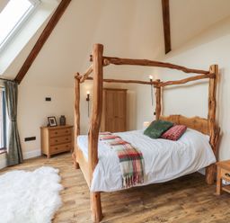 A bedroom with a wooden bed and rustic furniture at Yr Awen in Lampeter