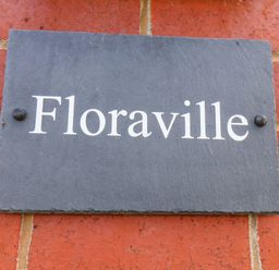 A slate sign with the name Floraville on a brick wall