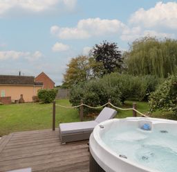 A garden with a hot tub and sun lounger at Harran in Pershore