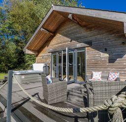 A wooden cabin with outdoor furniture and a hot tub at Dwrgi in Llanybydder